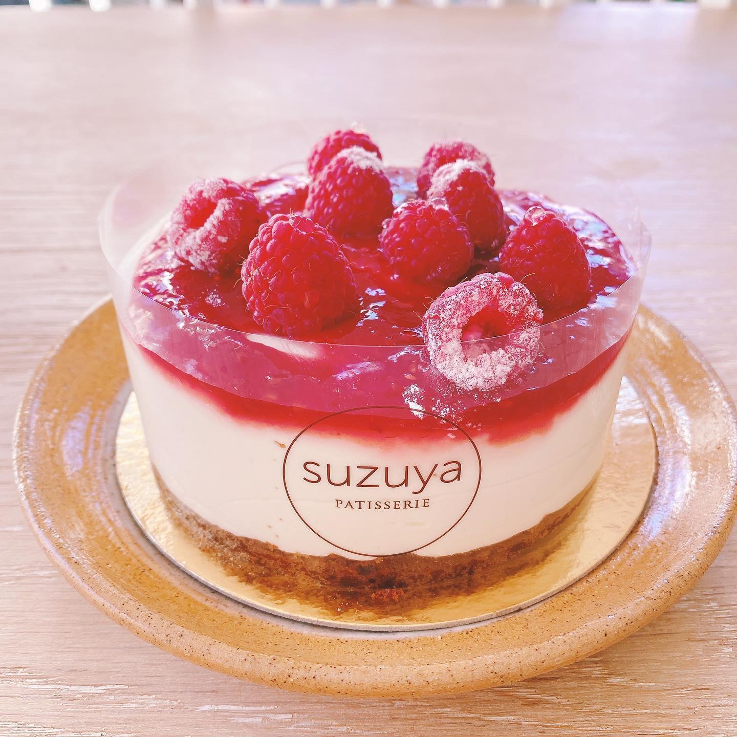 ラズベリーをのせたレアチーズケーキ。側面にsuzuya PATISSERIEのロゴ入りフィルムが巻かれている(並ぶ品は時期で変わります/Photo: @lets_go_eat_in_vegas / Used with permission)