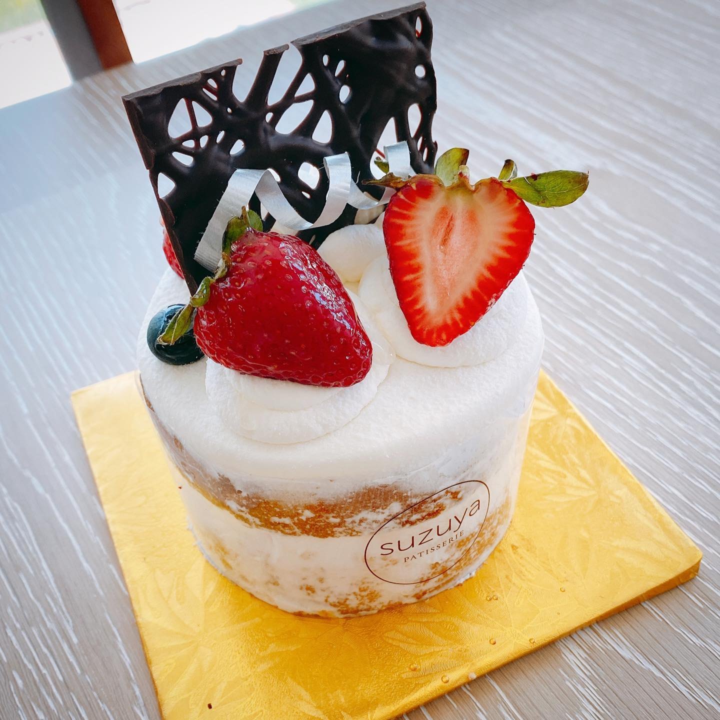 生クリームといちごをのせたショートケーキ。上に細工したチョコレートの飾りが立ててある(Photo: @lets_go_eat_in_vegas / Used with permission)